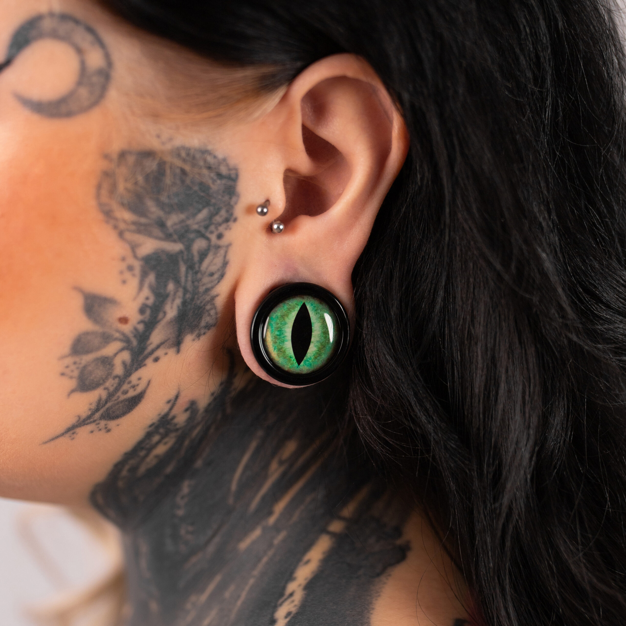 Verena Venus Plug vihreällä kissansilmällä Suuri vihreä kissansilmä-plugi tatuoidun henkilön korvassa