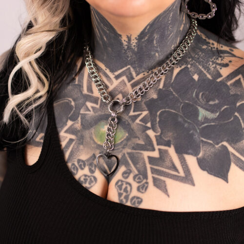 Hopeinen choker-koru sydämenmuotoisella riipuksella tatuoidulla iholla