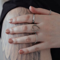 Hopeinen sydänsormus kirurginteräksestä kädessä tatuoidulla käsivarrella