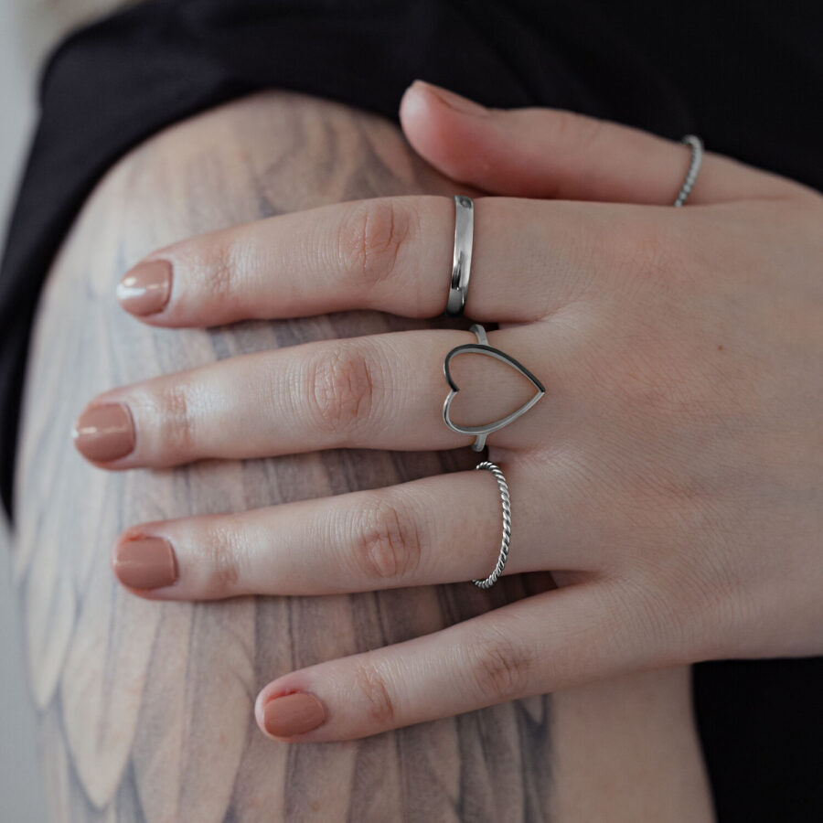 Hopeinen sydänsormus kirurginteräksestä kädessä tatuoidulla käsivarrella