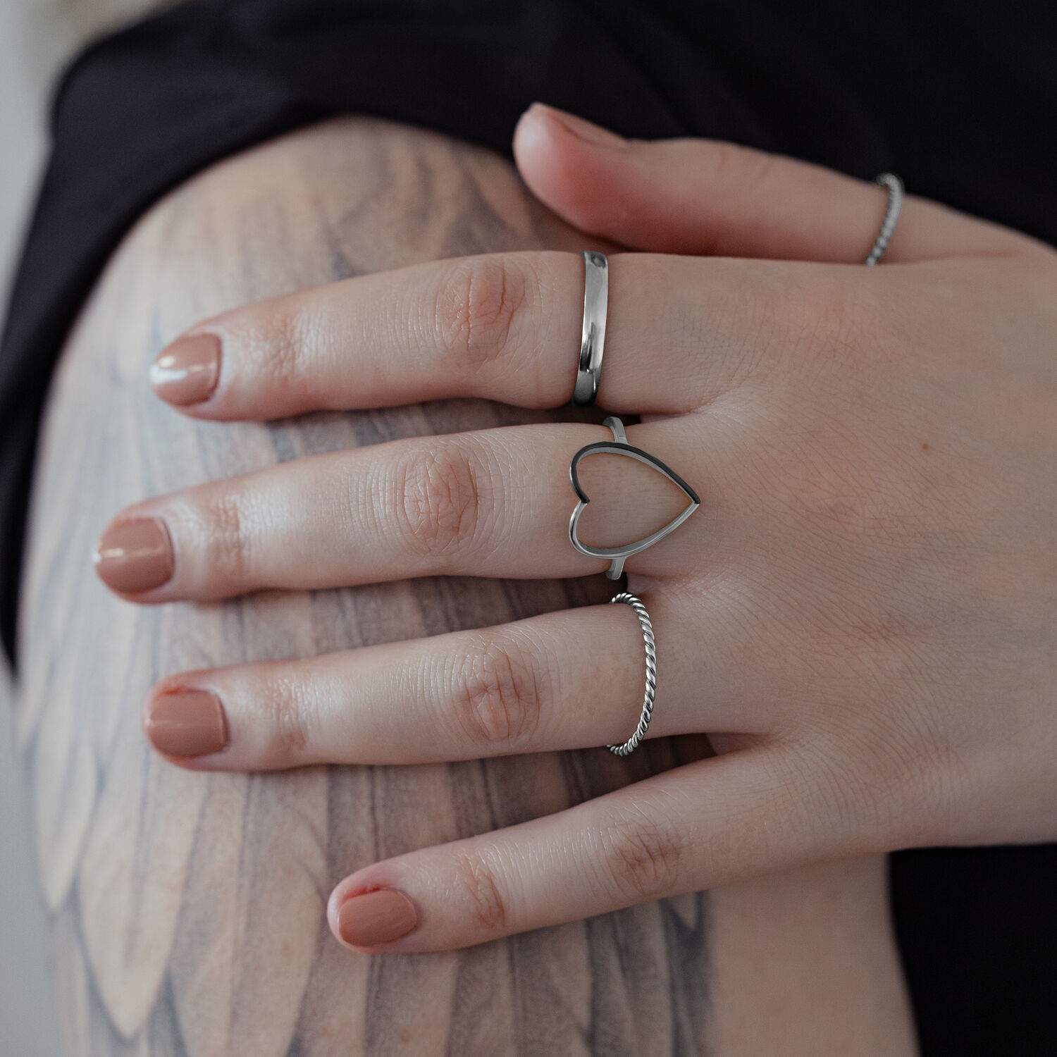 Hopeinen sydänsormus kirurginteräksestä kädessä tatuoidulla käsivarrella