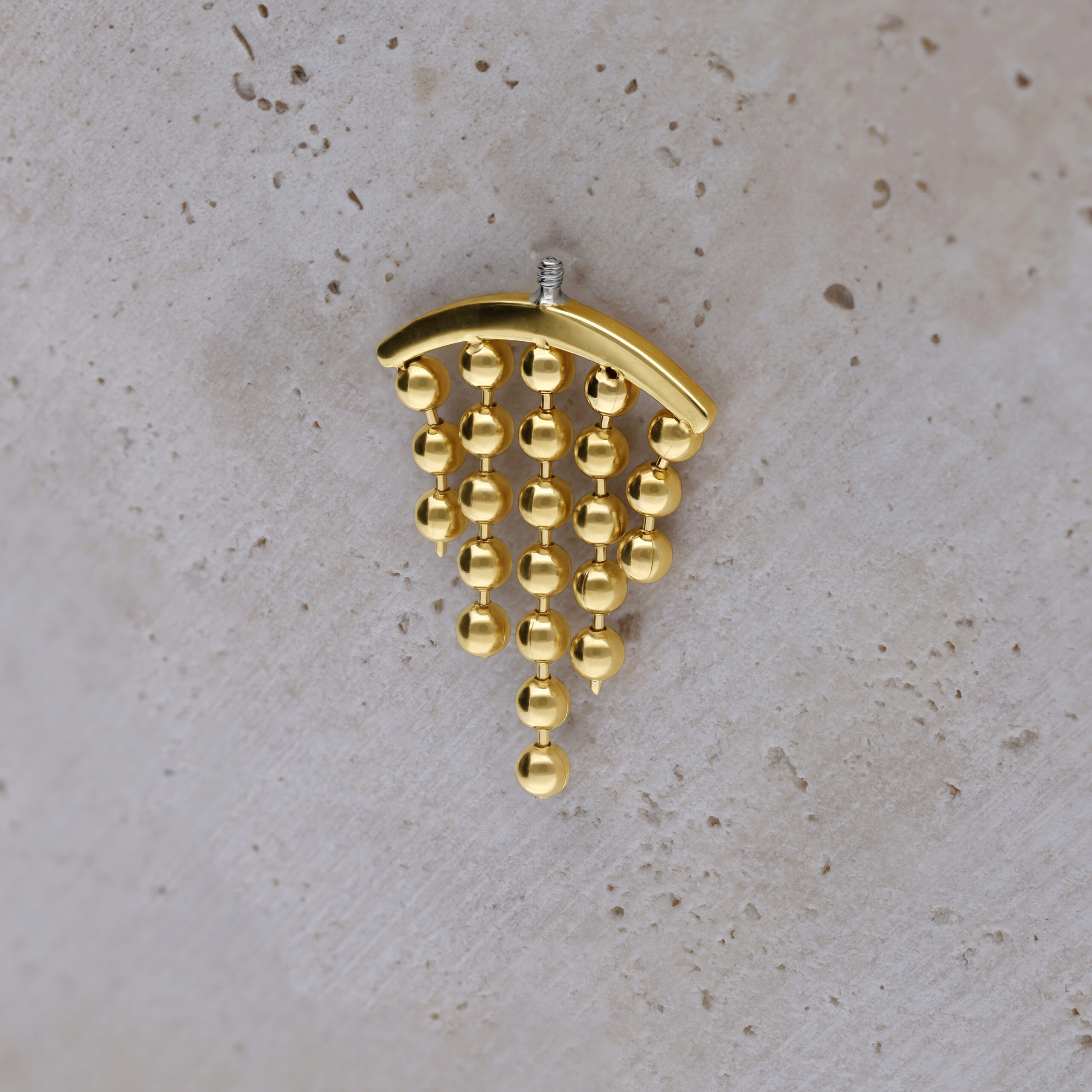Tyylikäs kultainen lisäosa helix-lävistykseen Kultainen helix-lävistyslisäosa roikkuvilla palloilla vaalealla taustalla
