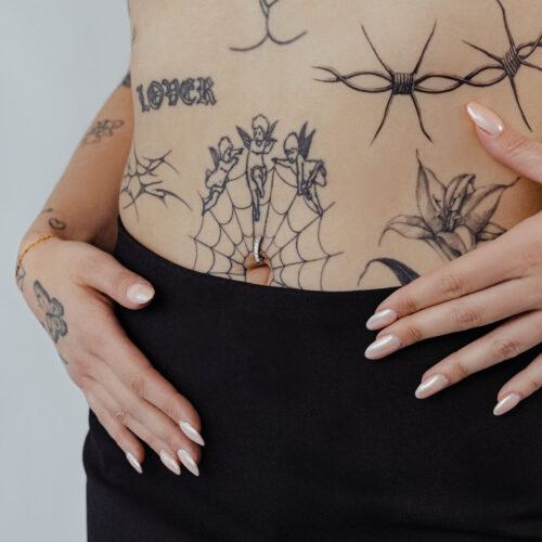 Napakoru mustalla kristalli-clickerillä ja tatuoinnit vaalealla iholla