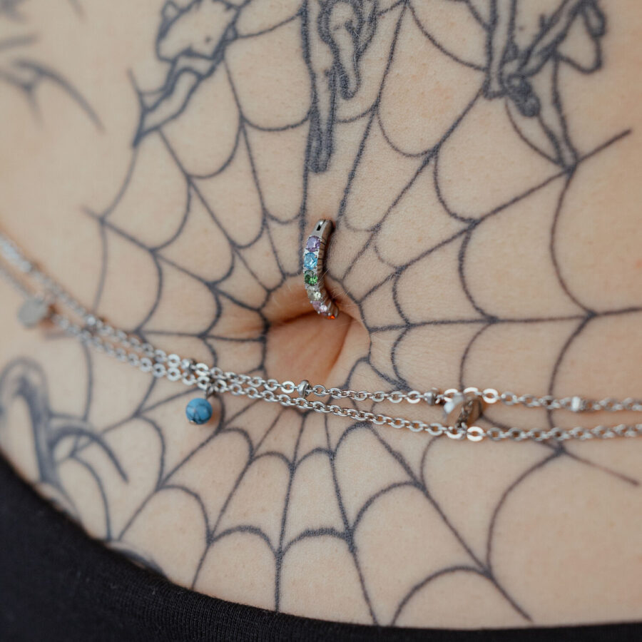 Napakoru sateenkaari-kristalleilla tatuoidulla iholla, lähikuva