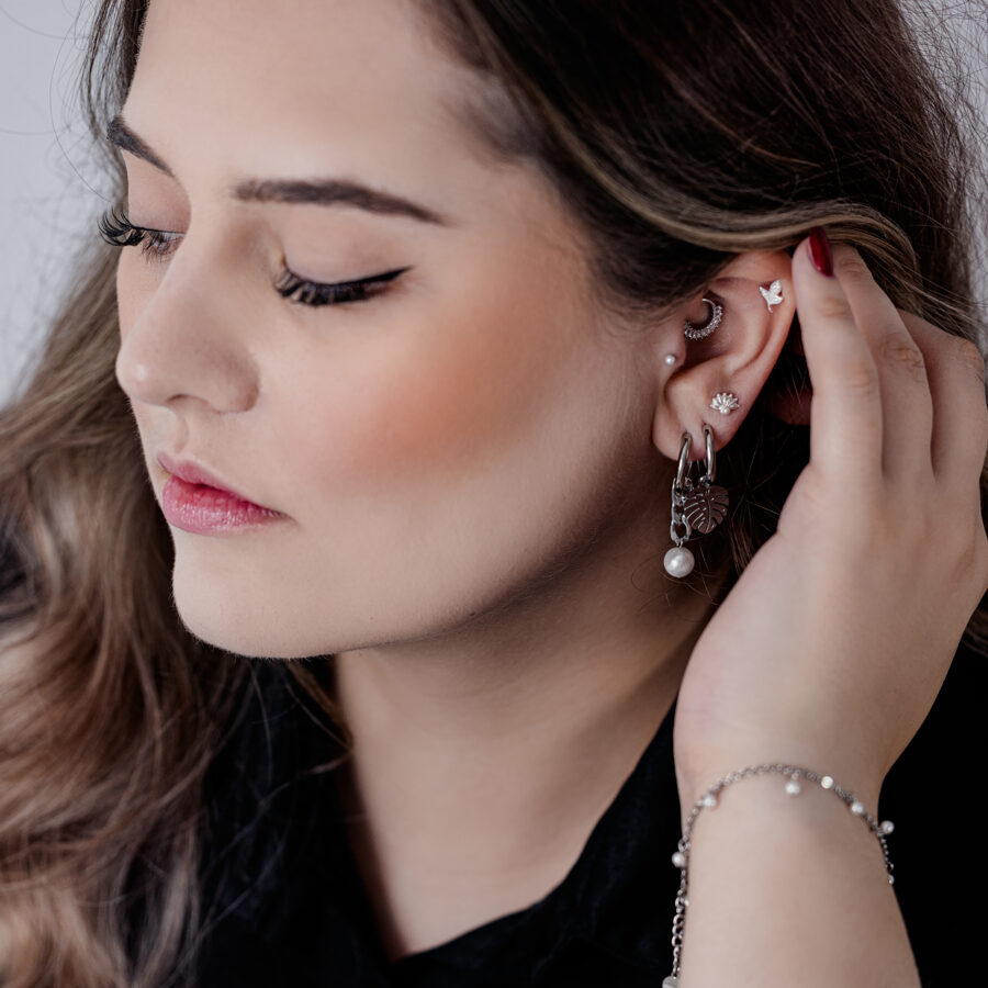 Nainen tyylikkäissä mustissa ja hopeisissa Chunky Pearl Hoops -korvakoruissa ja muissa korvakoruissa