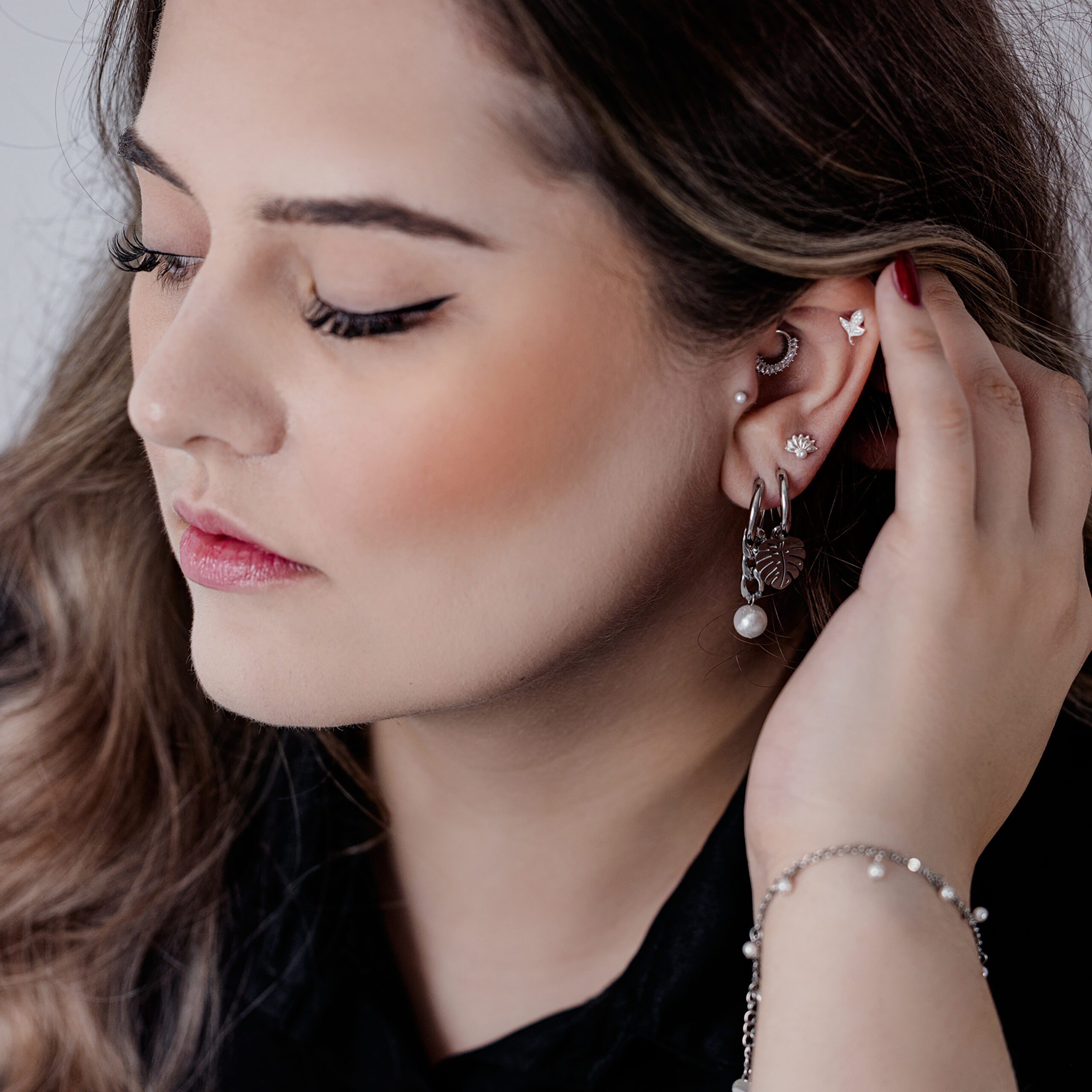 Tyylikkäät Chunky Pearl Hoops mustana ja hopeana Nainen tyylikkäissä mustissa ja hopeisissa Chunky Pearl Hoops -korvakoruissa ja muissa korvakoruissa