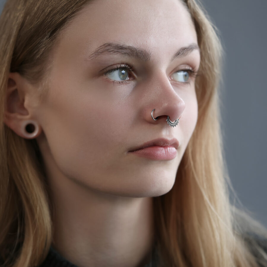 Nainen, jolla on hopeinen Wildcat septum-clicker, harmaa tausta