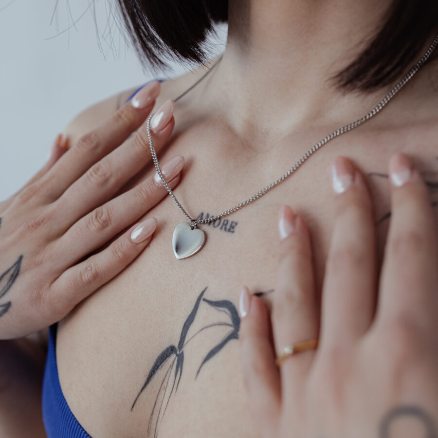 Hopeinen ketju kaiverrettavalla sydänriipuksella tatuoidulla iholla