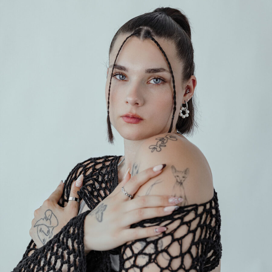 Nainen Little Pearl Circle Hoops -korvakoruilla ja mustalla yläosalla neutraalilla taustalla