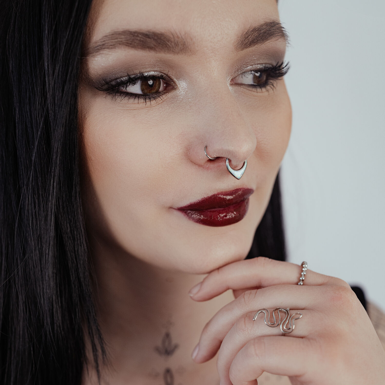 Chunky Opal Septum Clicker hopeassa Nainen mustilla hiuksilla käyttää hopeista septum clickeriä opaalilla vaalealla taustalla