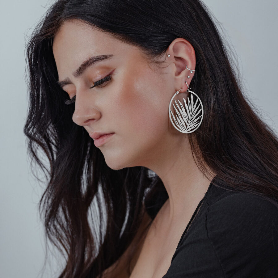 Hopeiset Noble Leaf Hoops -korvakorut naisella, jolla on pitkät, tummat hiukset