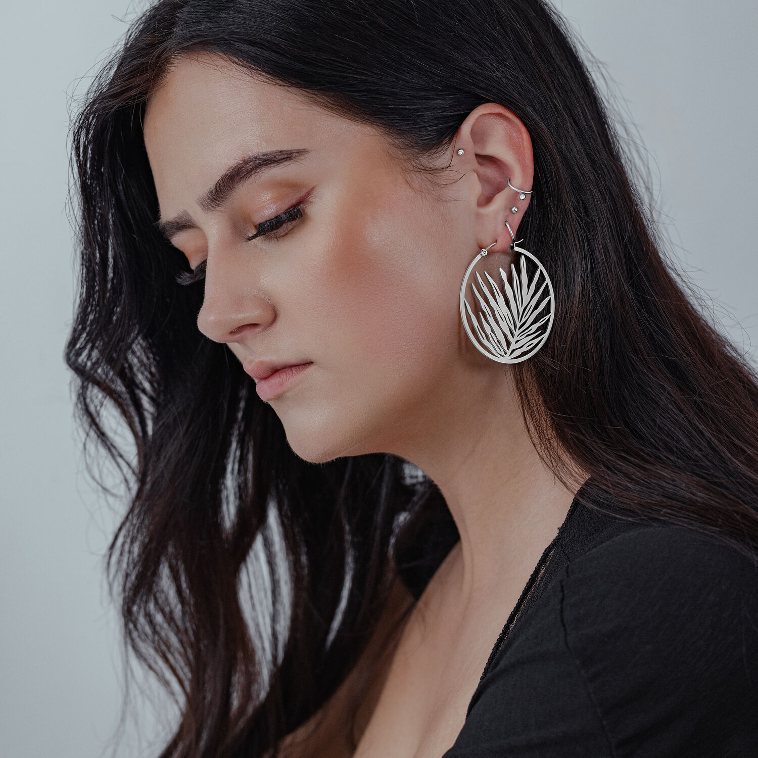 Hopeiset Noble Leaf Hoops -korvakorut naisella, jolla on pitkät, tummat hiukset
