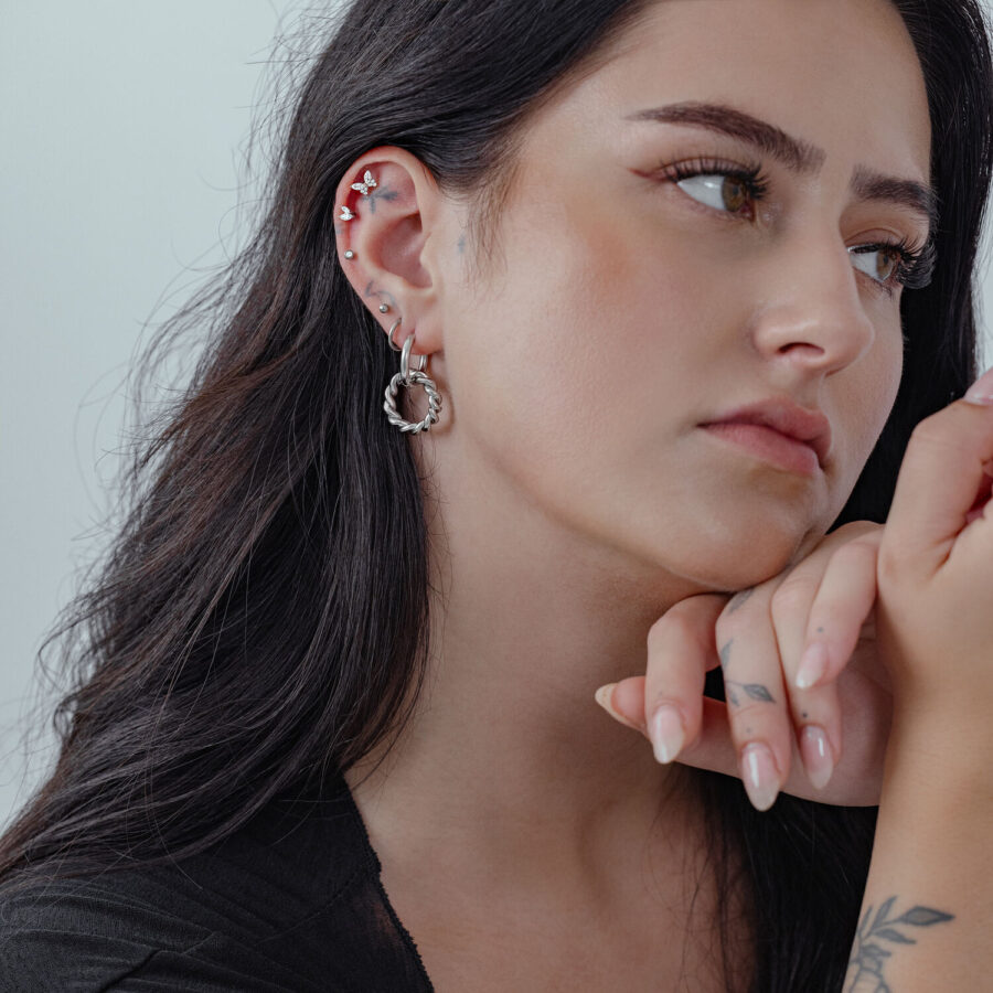 Pitkähiuksinen nainen käyttää hopeisia Twisted Circle Hoops -korvakoruja, sivuprofiili