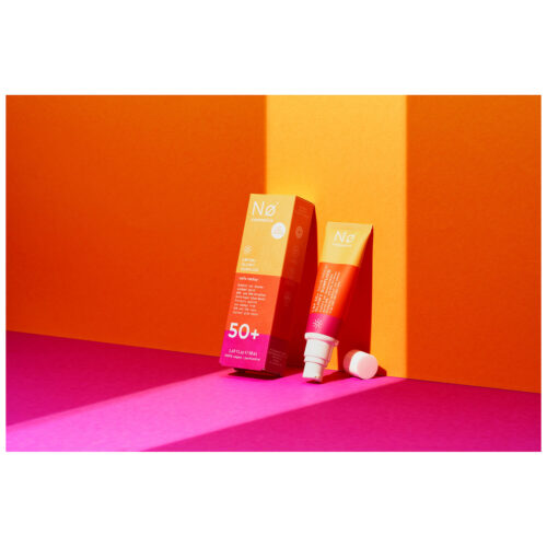 No Cosmetics Glowy Sunfluid tuubissa oranssin ja pinkin taustan edessä