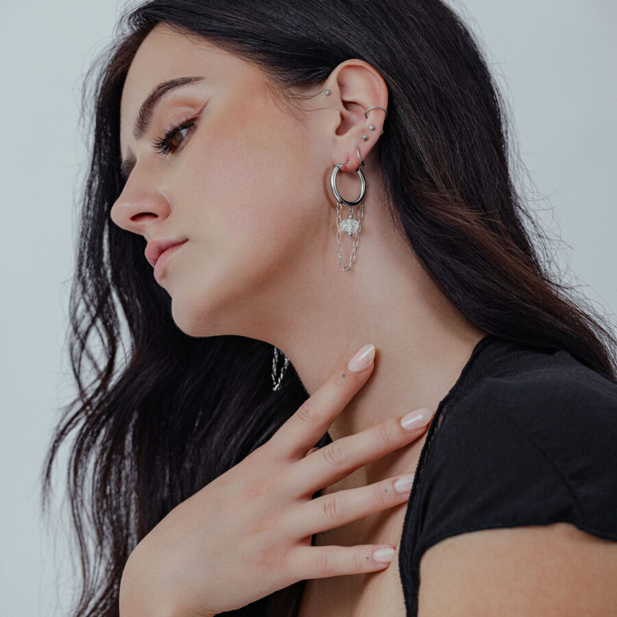 Pitkähiuksinen nainen, jolla on valkoiset Stone Hoops -korvakorut kirurginteräksestä korvassa
