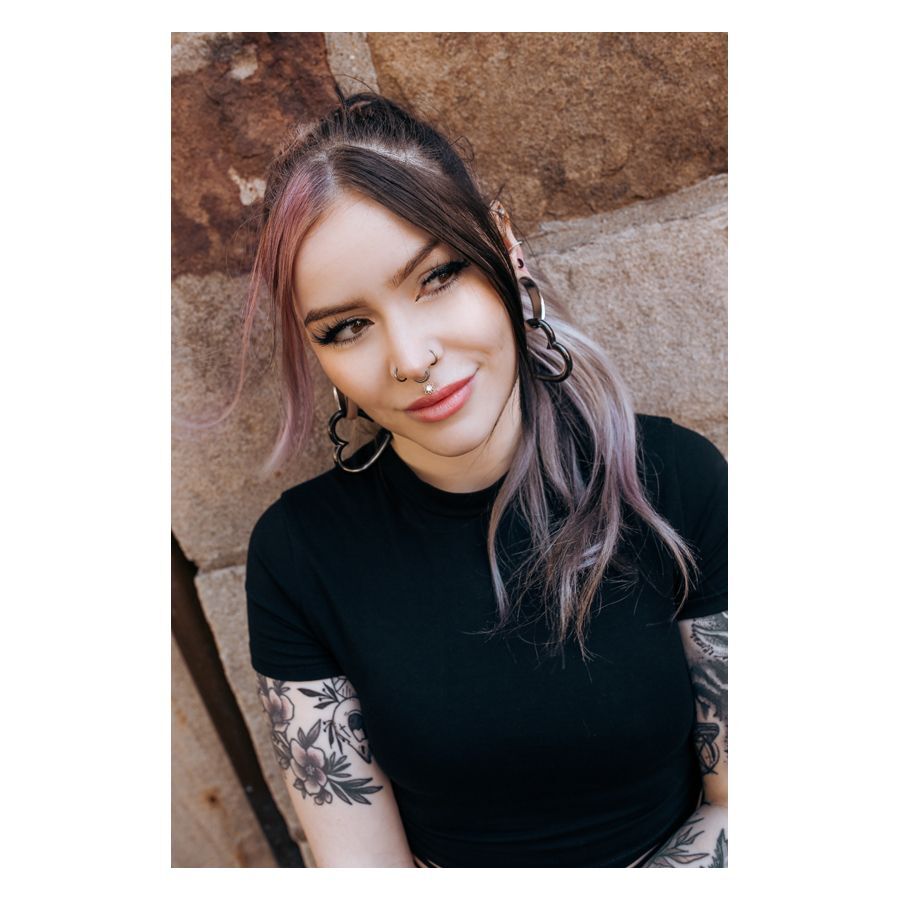 Concaver Septum Clicker mustana käytettynä Nainen mustan Concave Septum Clickerin kanssa ja pitkät hiukset kiviseinän edessä