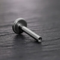 Titaani Labret-tappi sisäkierteellä, musta Musta titaani Labret-tappi sisäkierteellä mustalla taustalla
