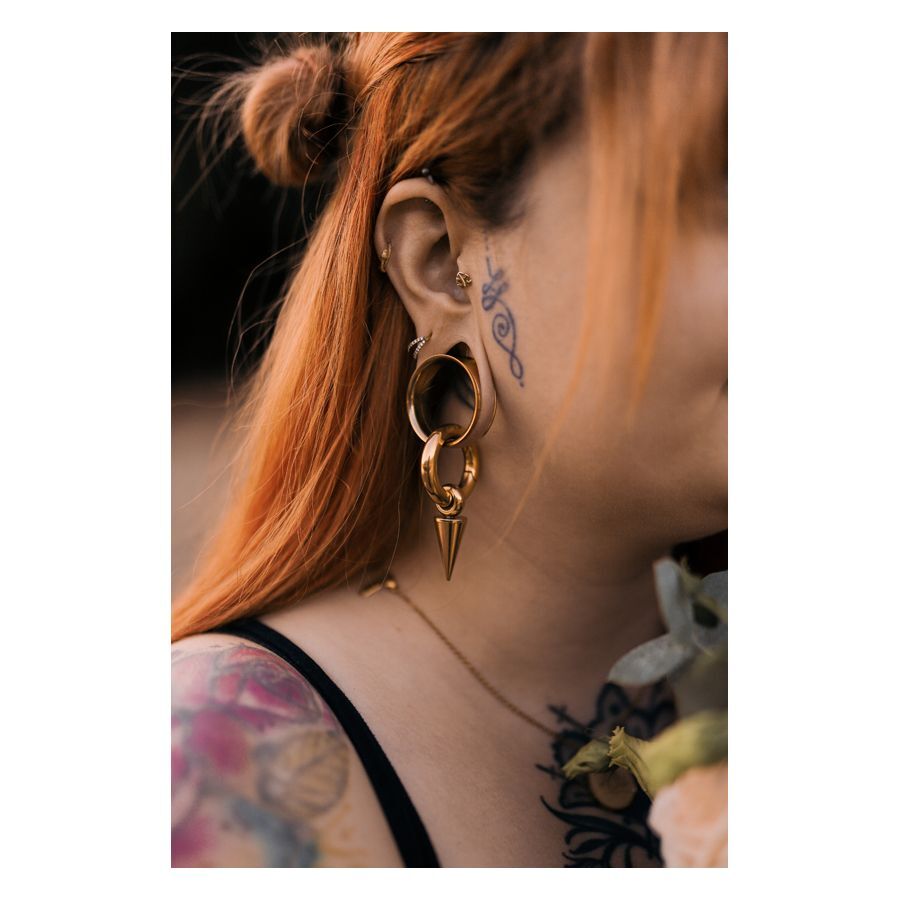 Kultainen Monstera Push-Fit Labret korvassa Punahiuksinen nainen käyttää kultaista Monstera Push-Fit Labret korvassa, tatuoinnit näkyvissä