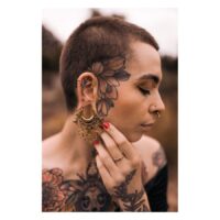 Mandala Labret kirurginteräksestä kultaisena Henkilö, jolla on kultaiset Mandala Labret -lävistykset ja tatuointeja kasvoilla ja kehossa