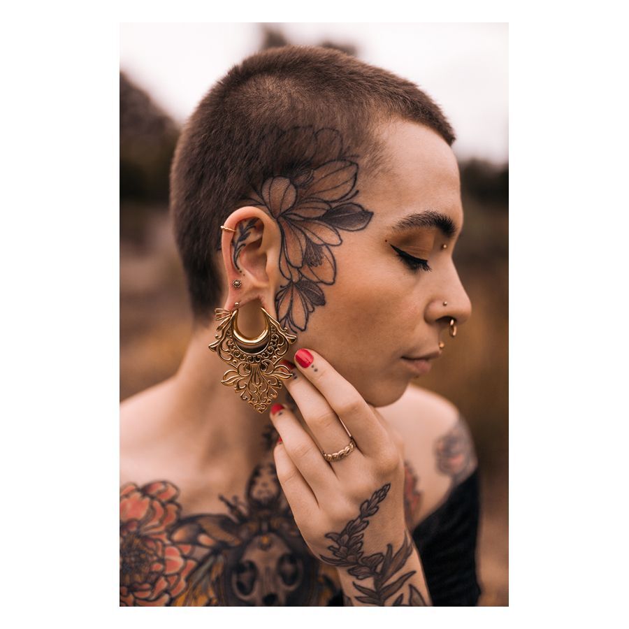 Mandala Labret kirurginteräksestä kultaisena Henkilö, jolla on kultaiset Mandala Labret -lävistykset ja tatuointeja kasvoilla ja kehossa
