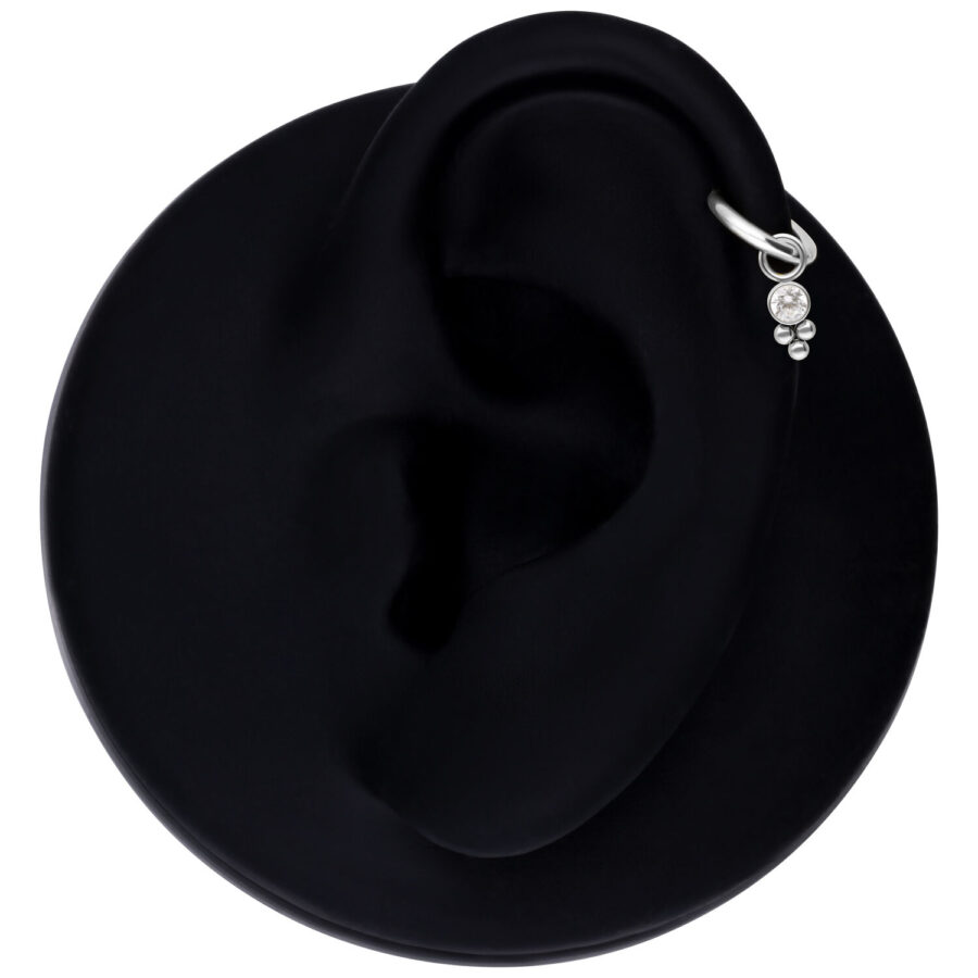 Hopeinen kristalli-piercing-riipus mustassa korvamallissa