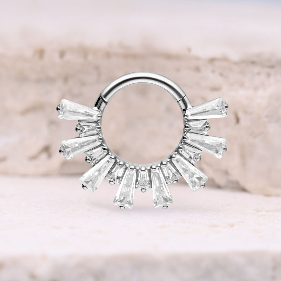 Hopeinen septum clicker kristalleilla vaalealla taustalla