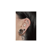 Hopeinen industrial-piercing korvassa Lähikuva korvasta, jossa hopeinen industrial-piercing ja muita korvakoruja