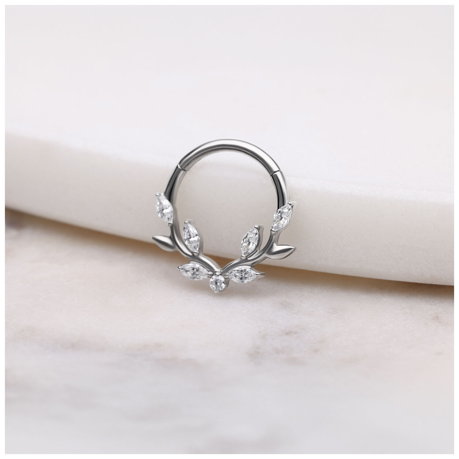 Hopeinen Septum Clicker kristallilehdillä valkoisella taustalla