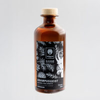 Wildcat Gin alkoholiton 0,35L pullo Ruskea lasipullo mustalla etiketillä, kasviaiheita, harmaa tausta