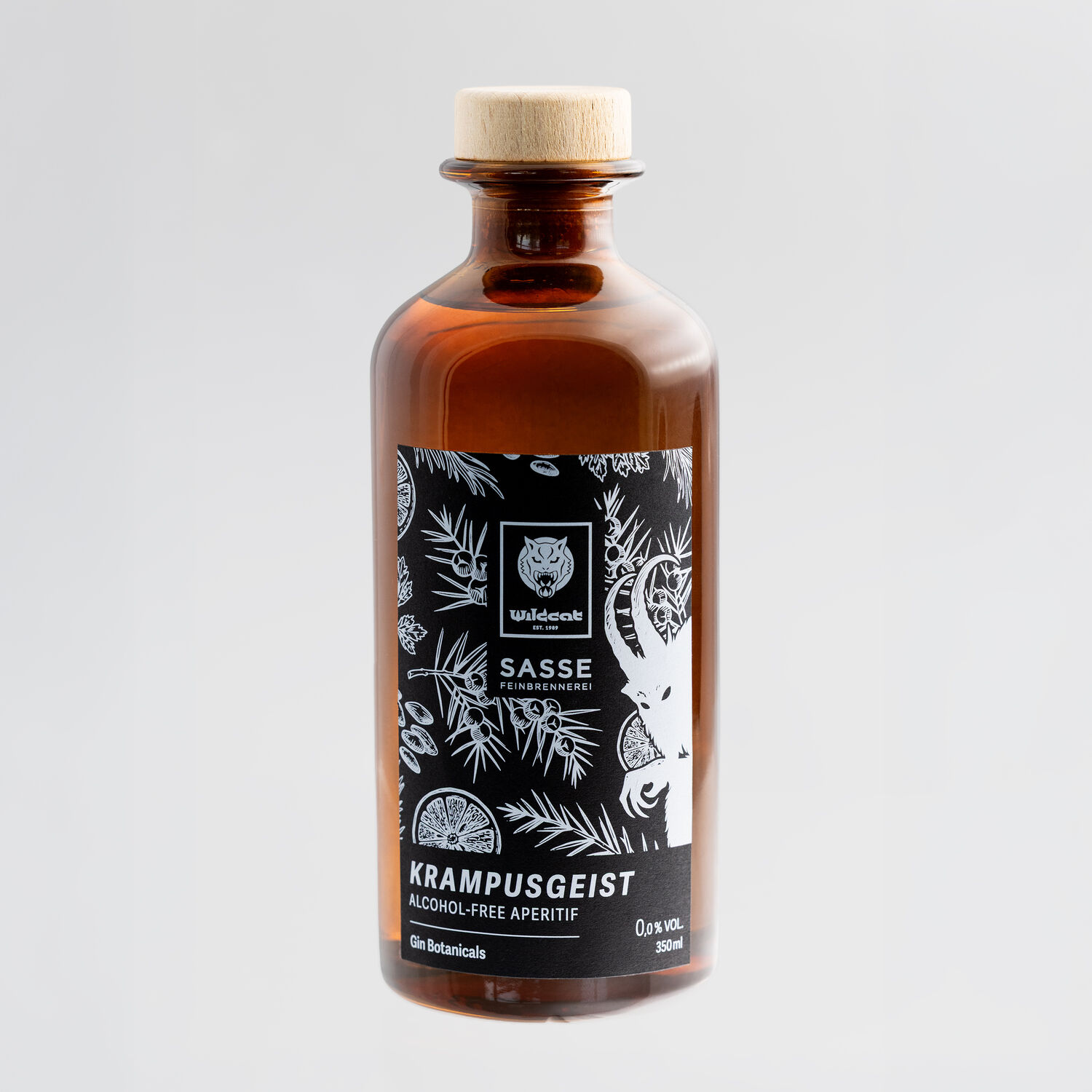 Wildcat Gin alkoholiton 0,35L pullo Ruskea lasipullo mustalla etiketillä, kasviaiheita, harmaa tausta