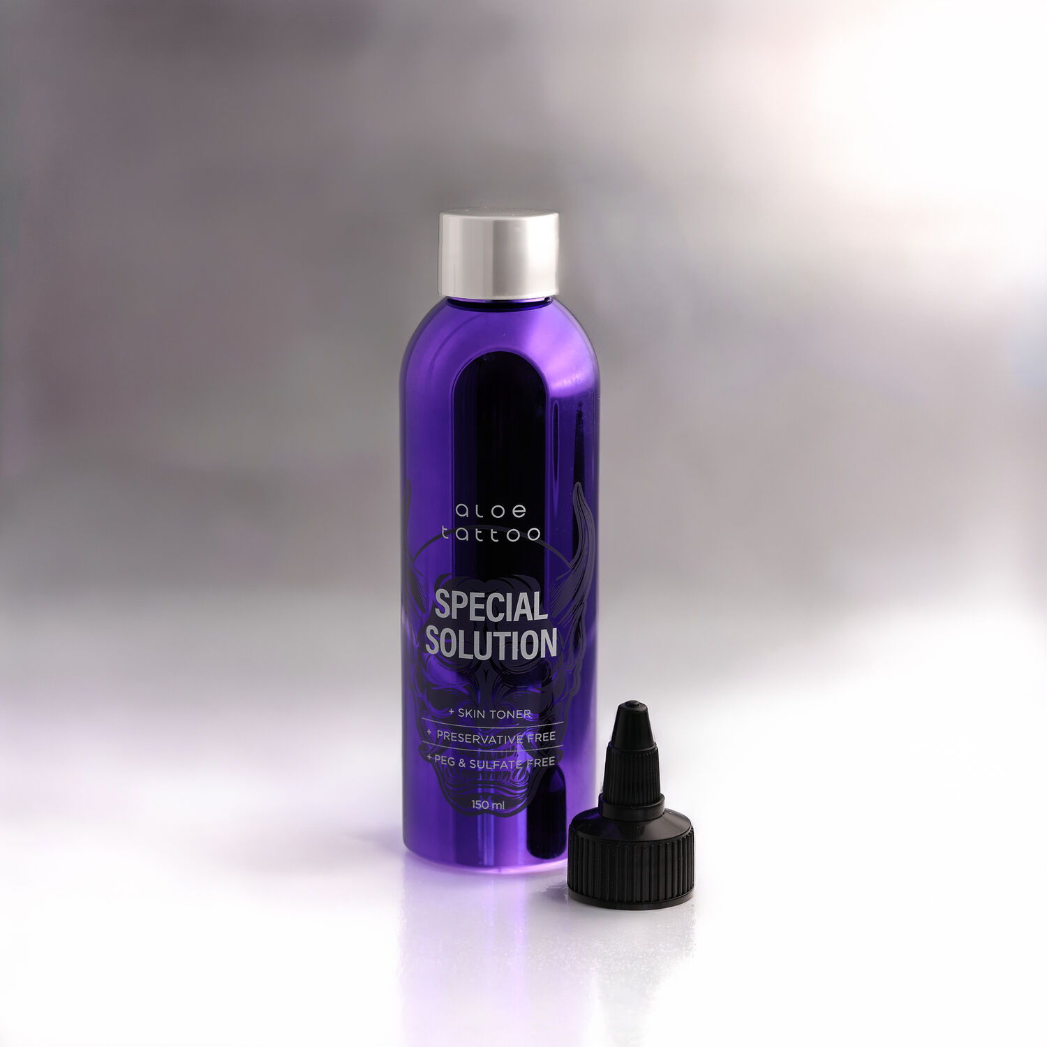 Violetti Aloe Tattoo Special Solution -pullo mustalla korkilla valkoisella taustalla