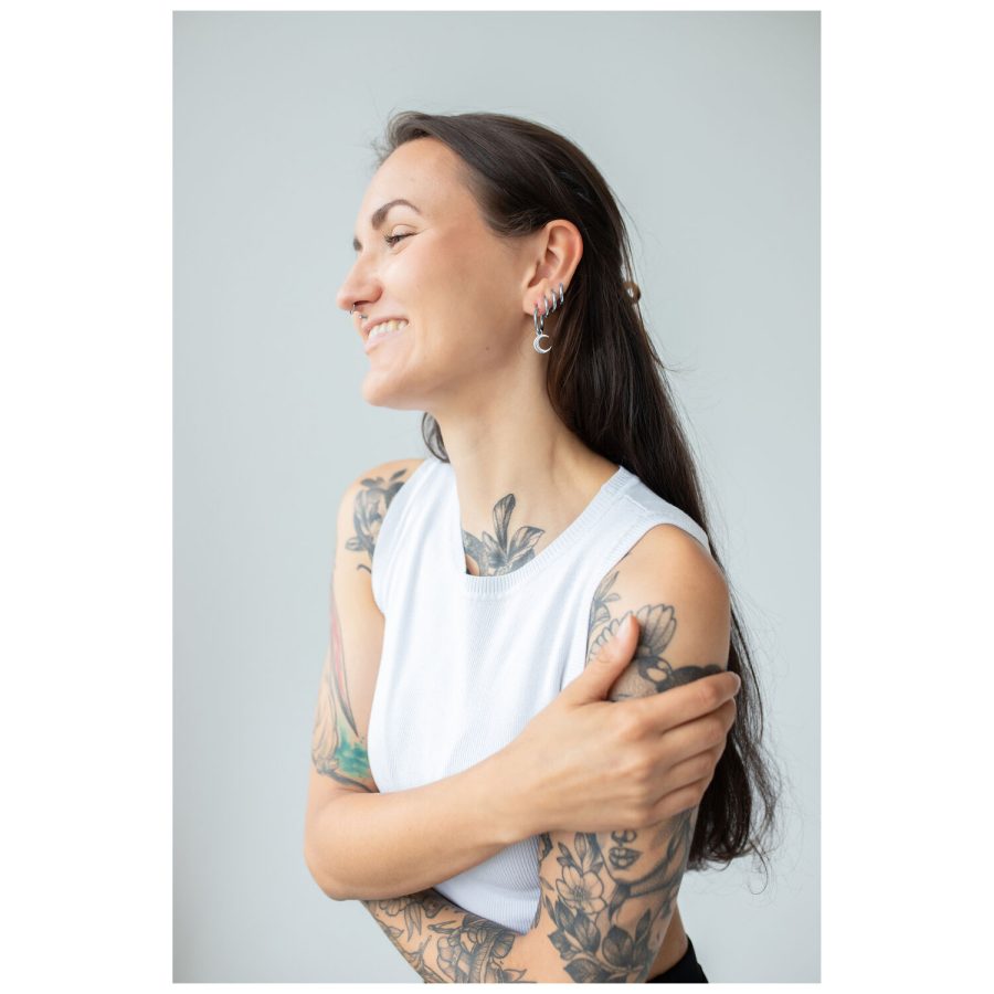 Nainen, jolla on tatuoidut käsivarret, käyttää hopeanvärisiä Little Moonchild -korvarenkaita
