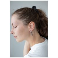 Nainen mustalla poninhännällä käyttää Little Flash Hoops -korvakoruja kirurginteräksestä
