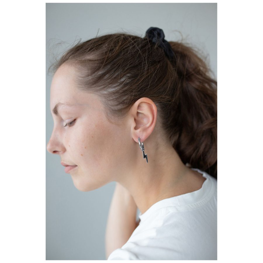 Nainen mustalla poninhännällä käyttää Little Flash Hoops -korvakoruja kirurginteräksestä