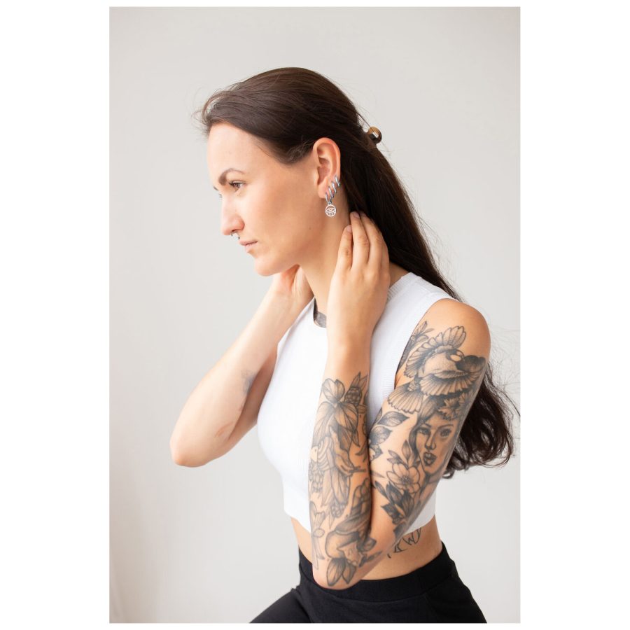 Pitkähiuksinen ja tatuoitu nainen käyttää Little Eye Hoops -korvakoruja