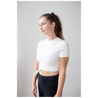 Nainen valkoisessa T-paidassa käyttää Little White Smiley Hoops -korvakoruja valkoista taustaa vasten
