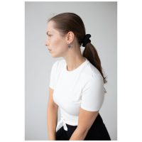 Nainen valkoisessa paidassa käyttää hopeisia Little Soulmate Hoops -korvakoruja harmaata taustaa vasten