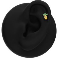 Kultainen ananas koru vihreillä lehdillä mustalla korva-alustalla