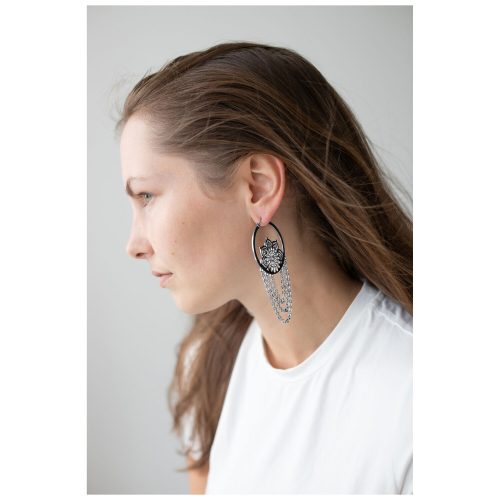 Pitkähiuksinen nainen käyttää mustia ja hopeisia La Fleur Hoops -korvakoruja