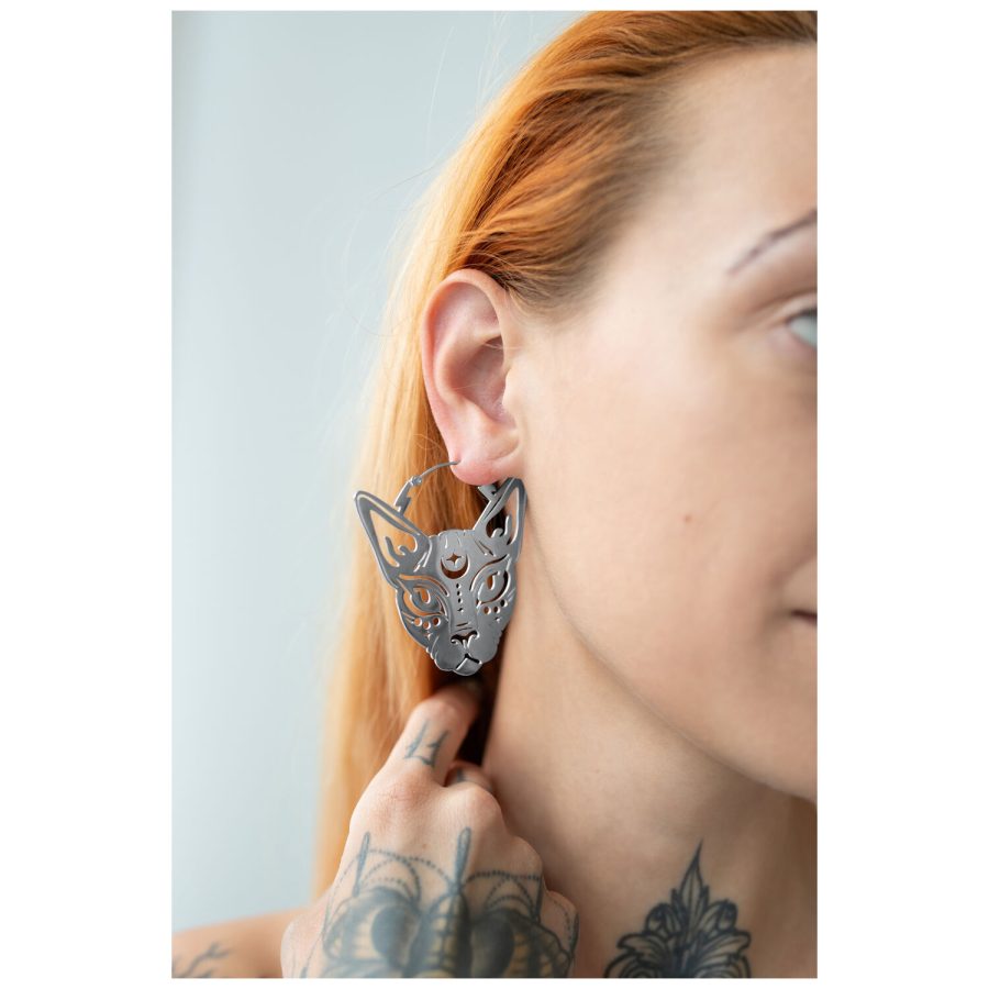 Hopeiset Sphynx Hoops korvarenkaat korvassa tatuoidun käden kanssa