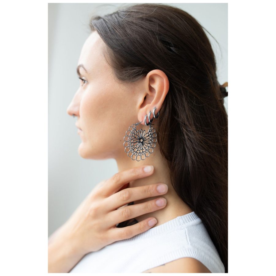 Nainen Daisy Hoops -korvakoruilla mustasta ja hopeisesta kirurginteräksestä.