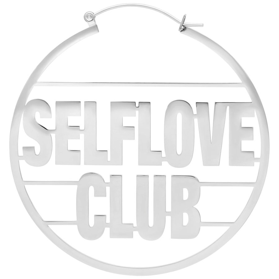 Hopeinen korvakoru, jossa 'Selflove Club' -teksti valkoisella taustalla