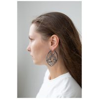 Pitkähiuksinen nainen käyttää suuria mustia Lotus Hoops -korvakoruja