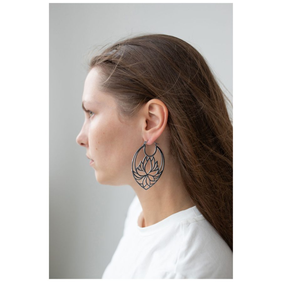 Pitkähiuksinen nainen käyttää suuria mustia Lotus Hoops -korvakoruja