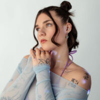 Sininen mesh-toppi tatuointikuviolla Nainen sinisessä mesh-topissa ja tatuointikuviolla valkoisella taustalla