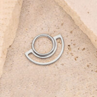 Hopeinen Dual Ring Clicker kivellä Hopeinen ring clicker beigellä kivipohjalla, pyöreä muotoilu