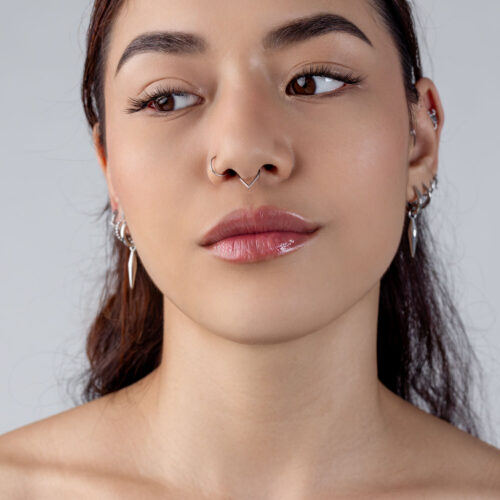 Nainen hopeisella Teardrop Clickerilla septumissa, neutraali tausta